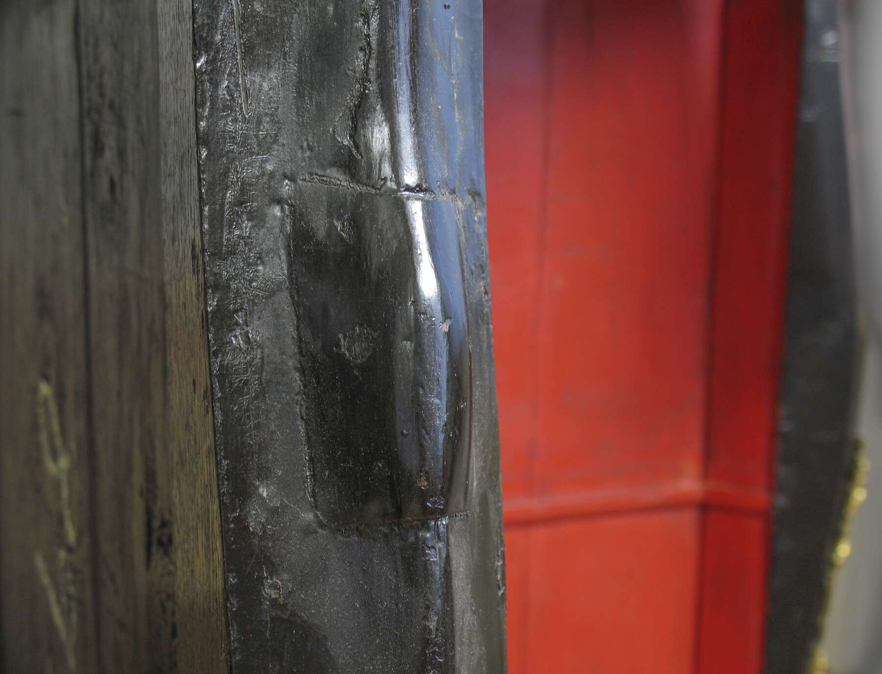 detail of a raised block of black wood on one of the front posts and red interior in the background