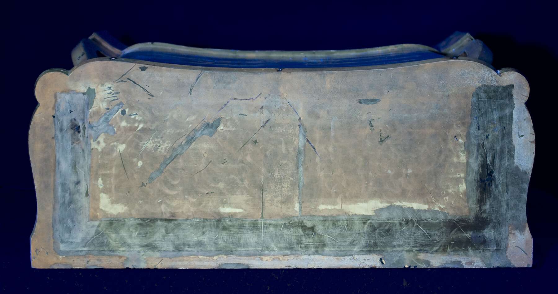 top of the bottom register as seen under ultraviolet light, revealing a c-shaped patch of veneer alongside the back and sides of the serre-papiers