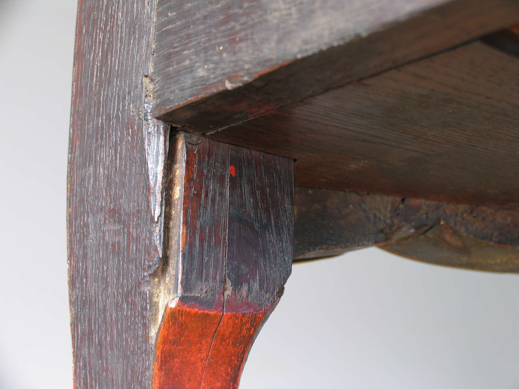 detail of one of the commode legs, showing the wood grain, underside of the desk, and a long vertical crease running down the leg