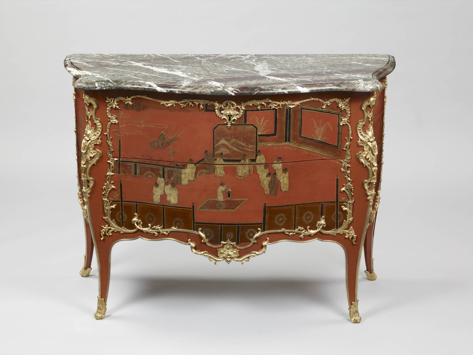 frontal view of an additional red lacquer commode decorated with gilt bronze mounts, black, and gold lacquer designs, and a green, red, and white veined marble top