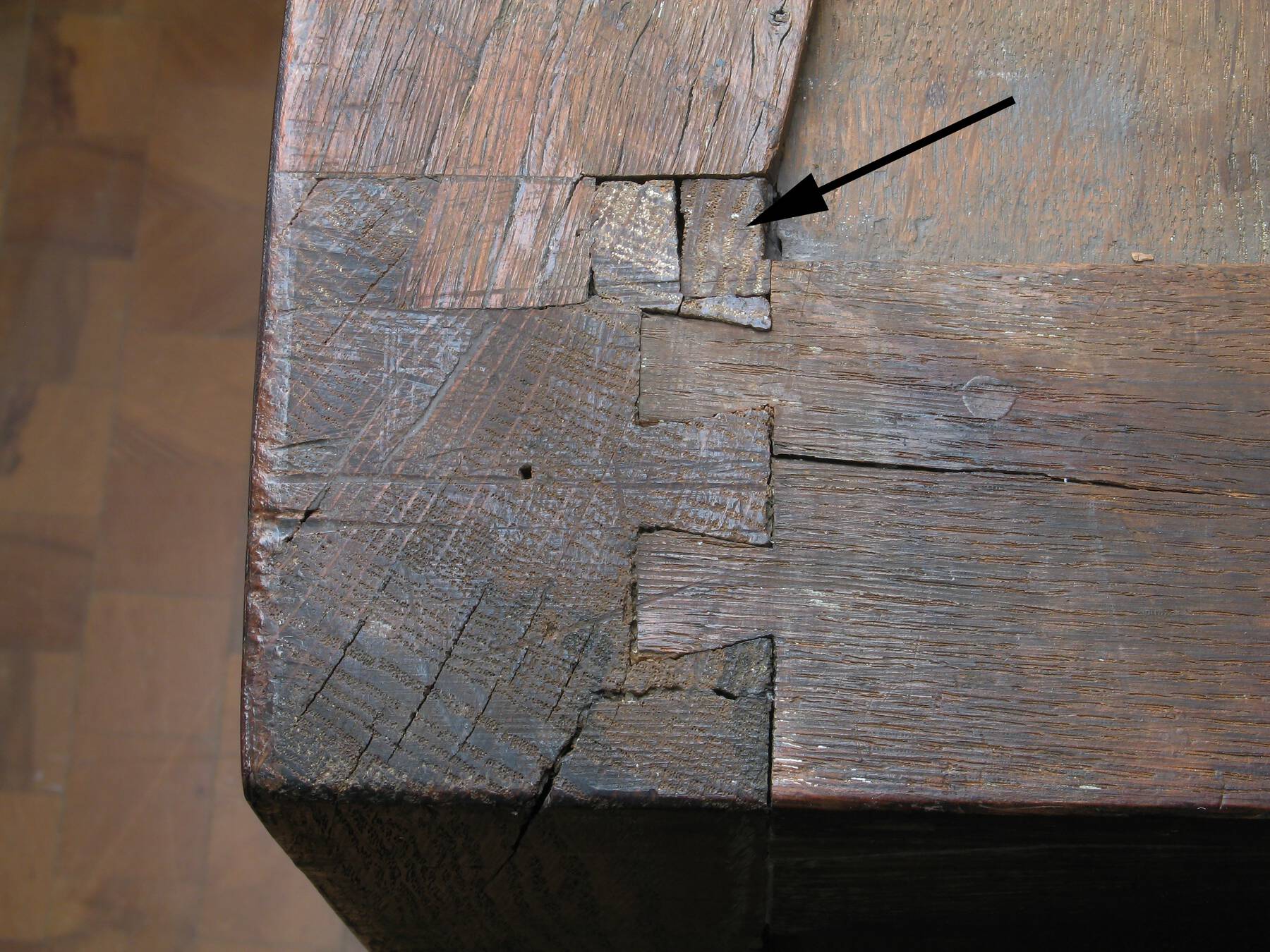 detail of one of the leg’s dovetail joints, with a black arrow superimposed onto the photograph to indicate where the final joint piece was inserted