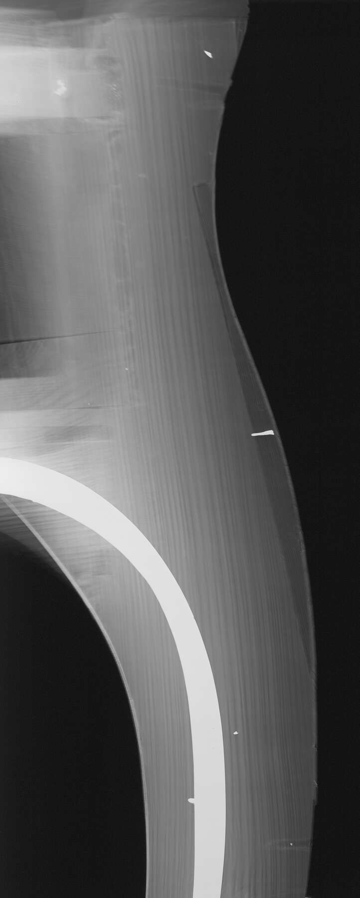 black and white x-ray of one of the desk legs, showing the wood in shades of gray with a white curved line running down the leg