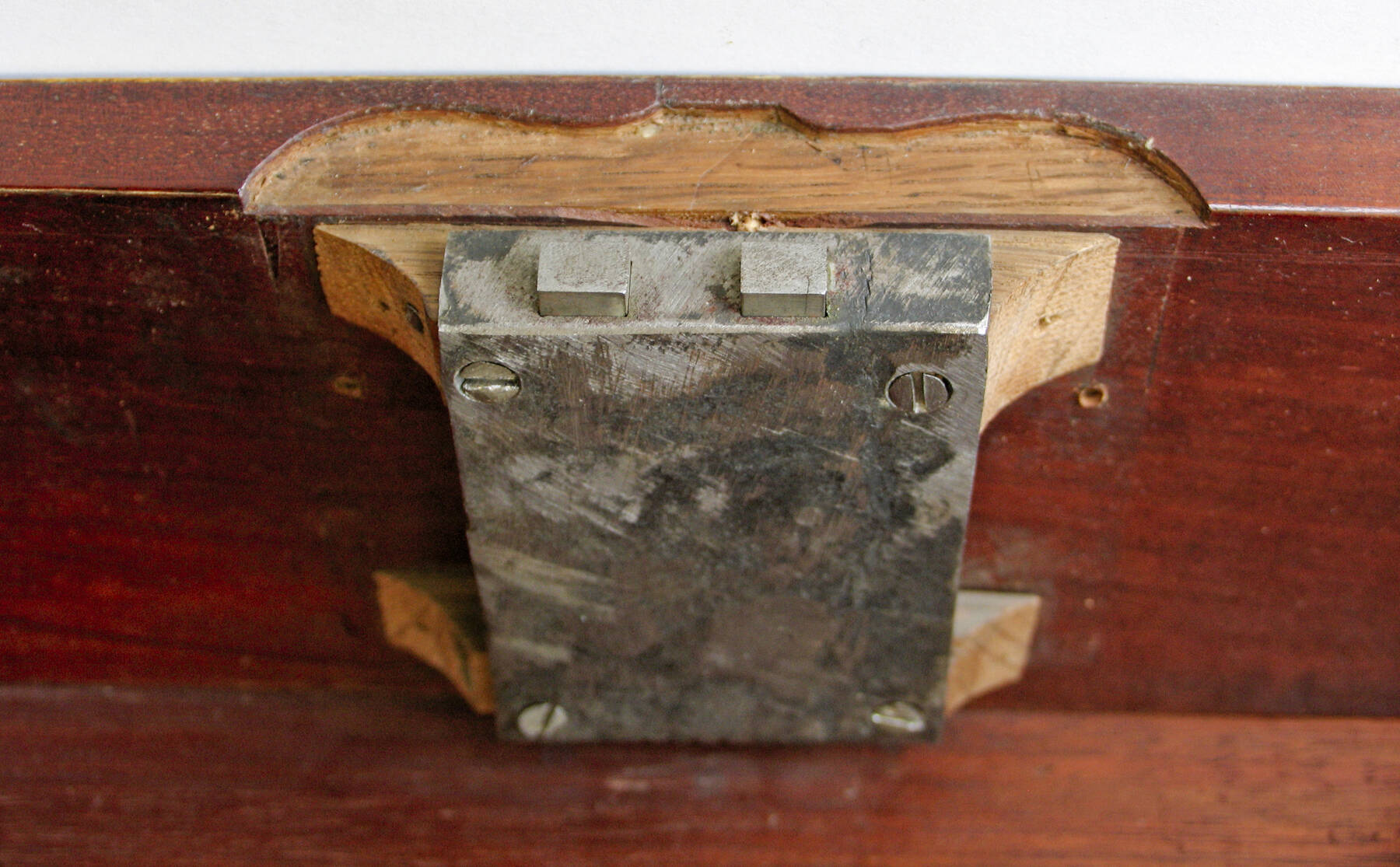 detail of one of the locking mechanisms, constructed of an iron rectangle with a nail at each corner and two smaller squares protruding from the top
