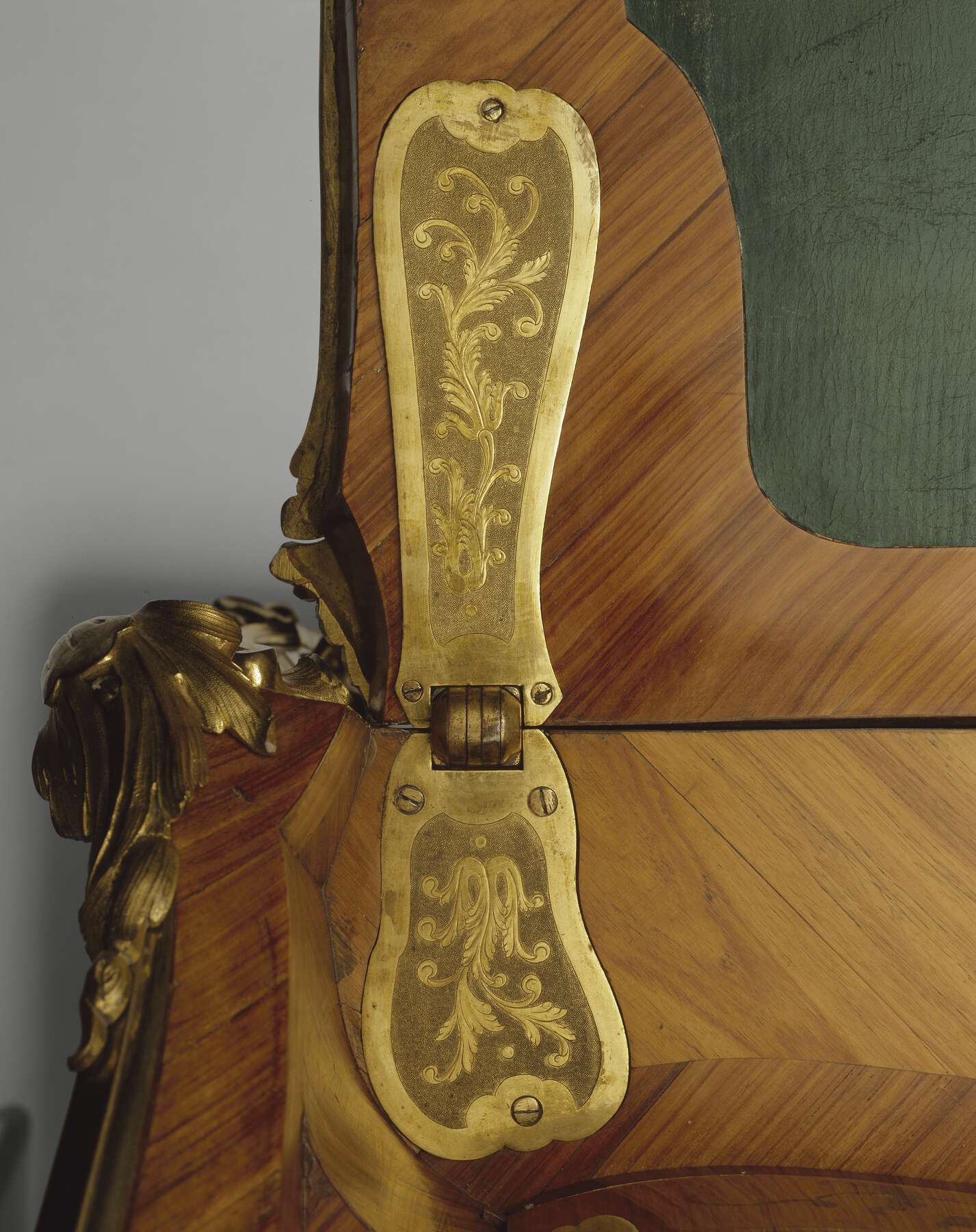 gilt bronze plates decorated with floral scrolls cover the desk’s inner hinges