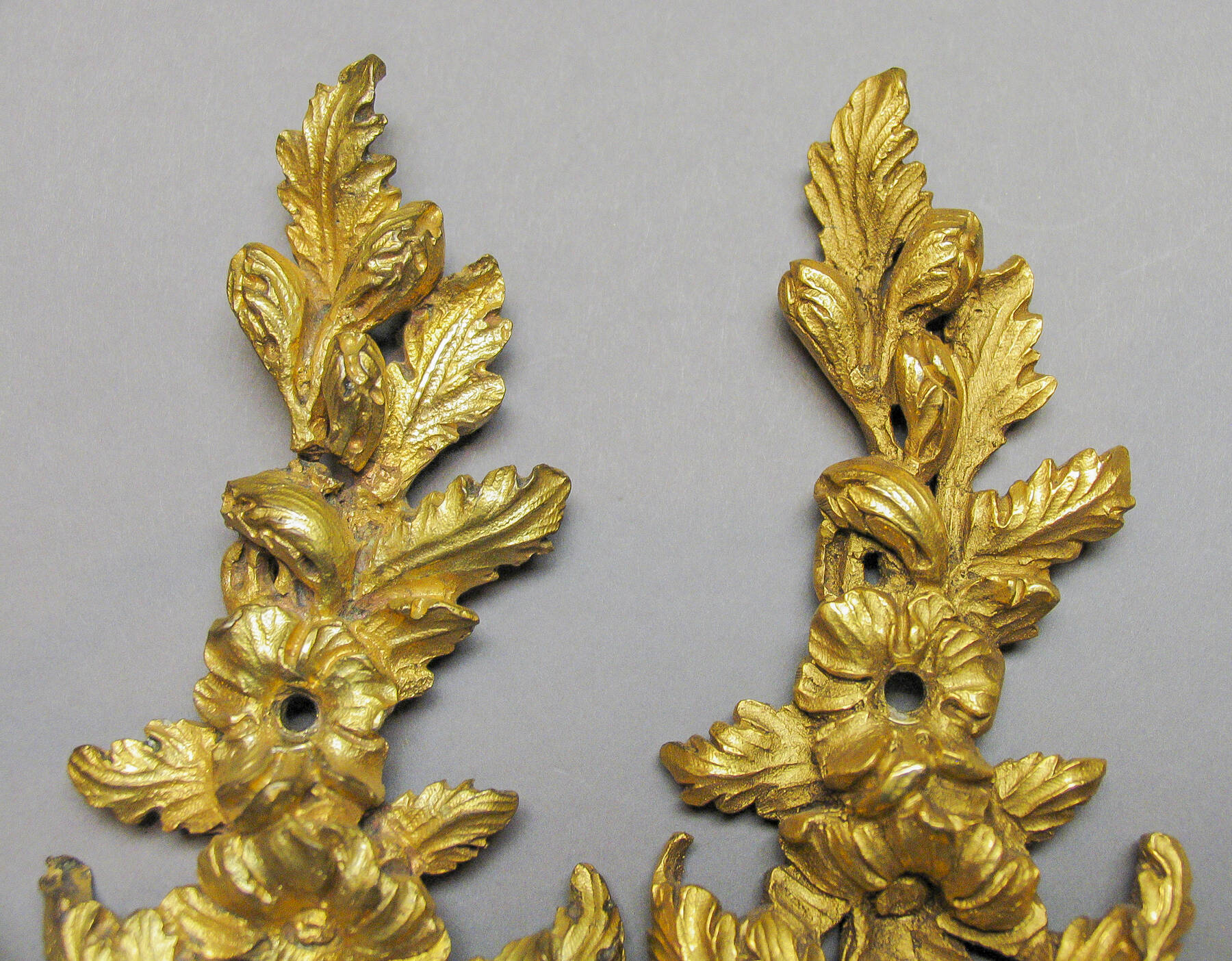 detail of two gilt bronze floral mounts, a reproduction on the left and an original on the right
