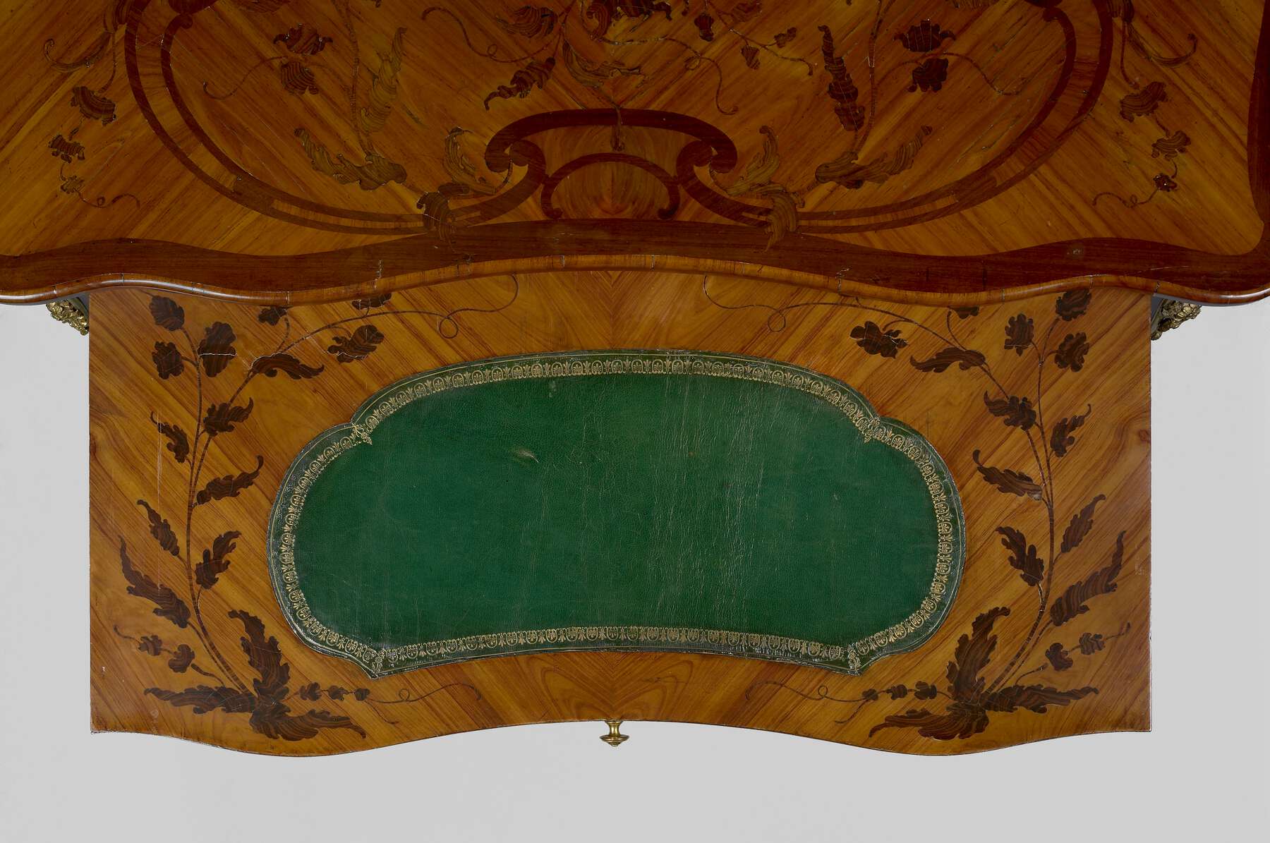 bird’s-eye view of the frontal slide, highlighting the marquetry of foliate designs that frames the oval-shaped green leather