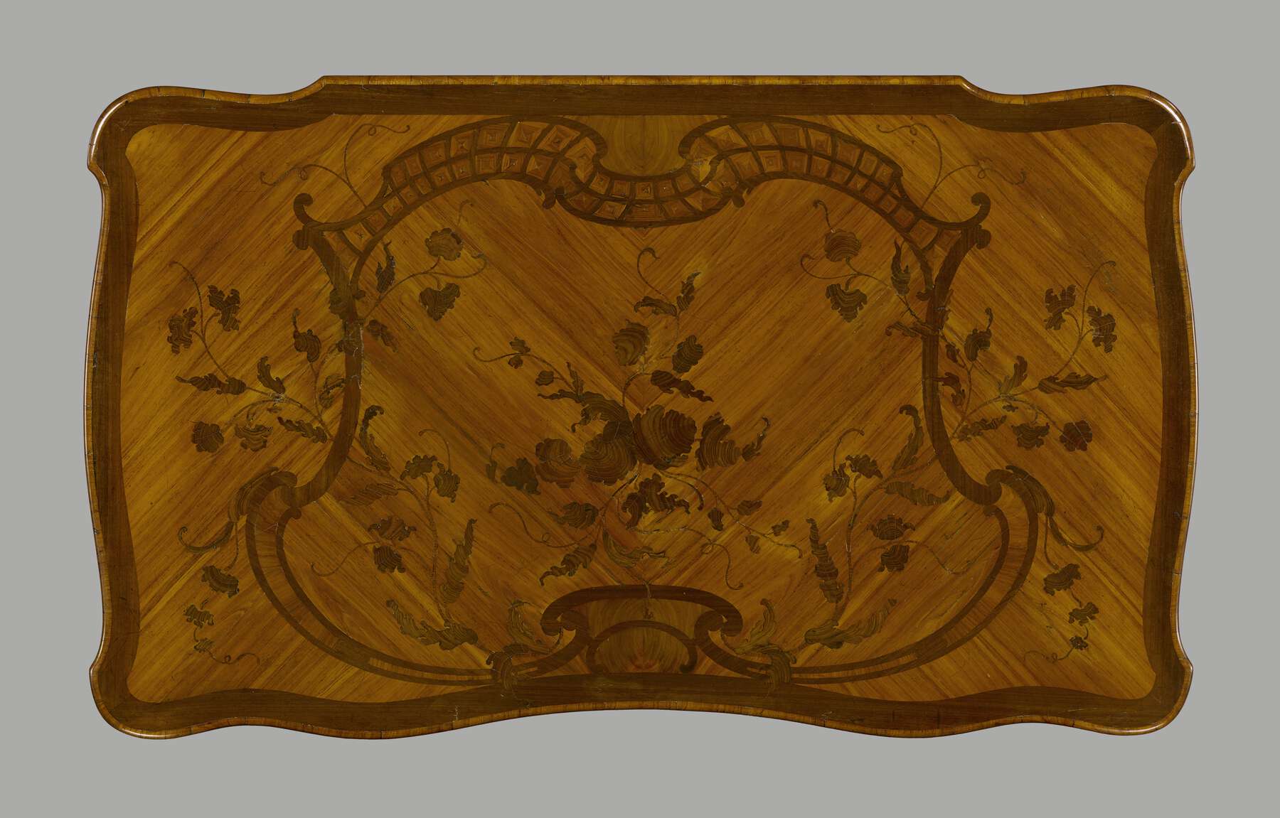 the table’s surface is decorated with wooden inlay arranged to highlight the grain background and a large marquetry in the middle of the table made of scrolls and floral designs